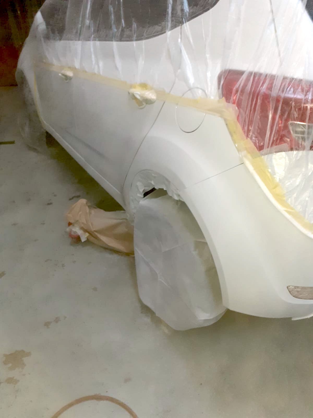 a white car wrapped in protective film and the repair to the body worked completed on the nearside rear.